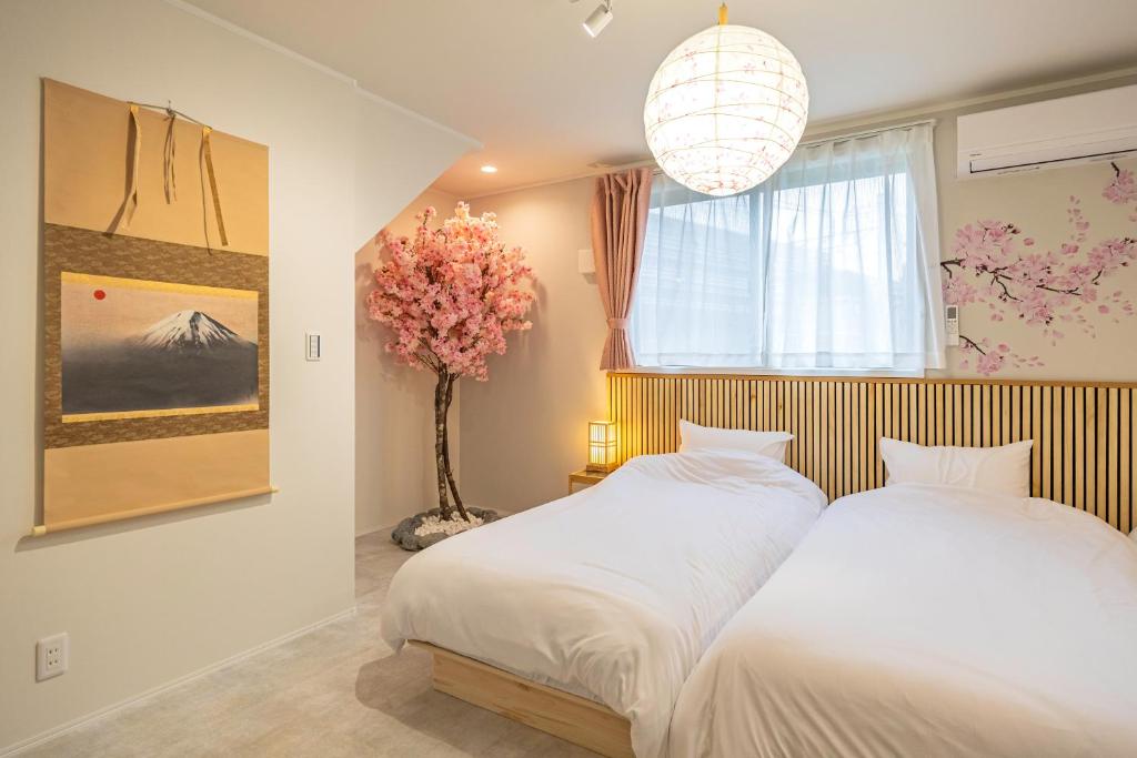 a bedroom with two beds and a vase with flowers at suite Funabashi SAKURA1 #102 in Funabashi