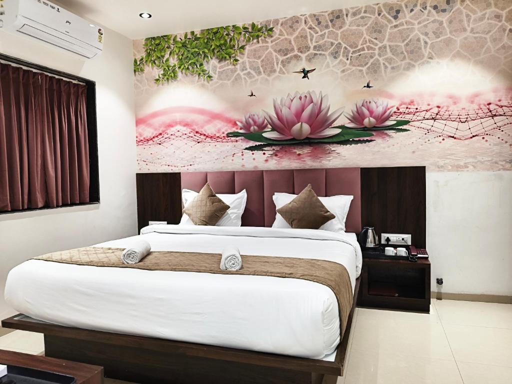 a bedroom with a large bed with flowers on the wall at Kings Executive and Restaurant in Tuljapur