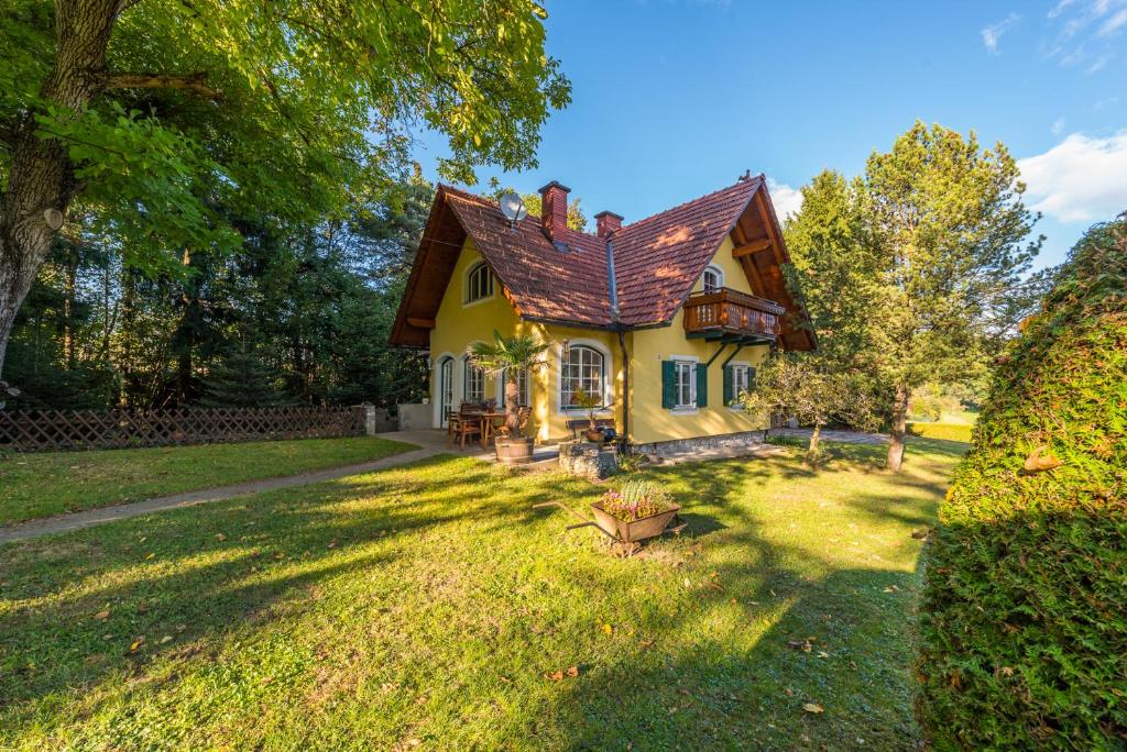 a yellow house with a brown roof on a yard at Winemakers Escape in Gleisdorf