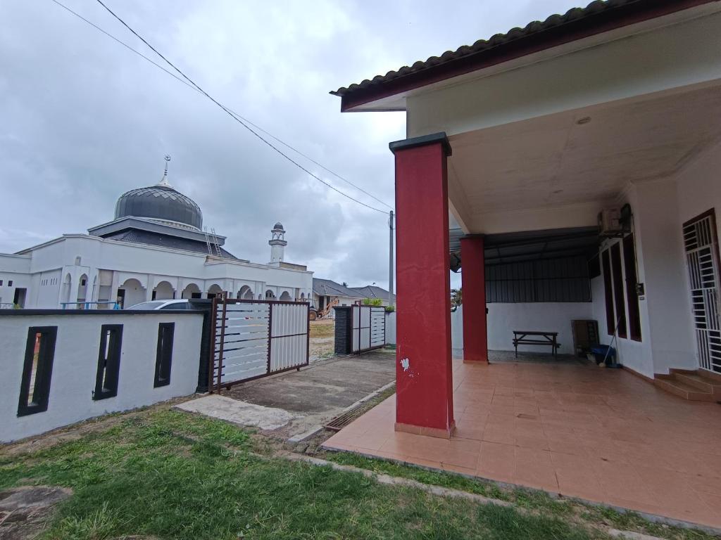 a white building with a red pole in front of it at NikNa Homestay Batu Rakit - WIFI Netflix in Kampong Ru Tujoh