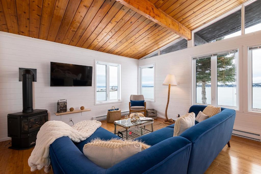 a living room with a blue couch and a stove at Hôtel à la maison - Cap à l'Ile in Les Éboulements