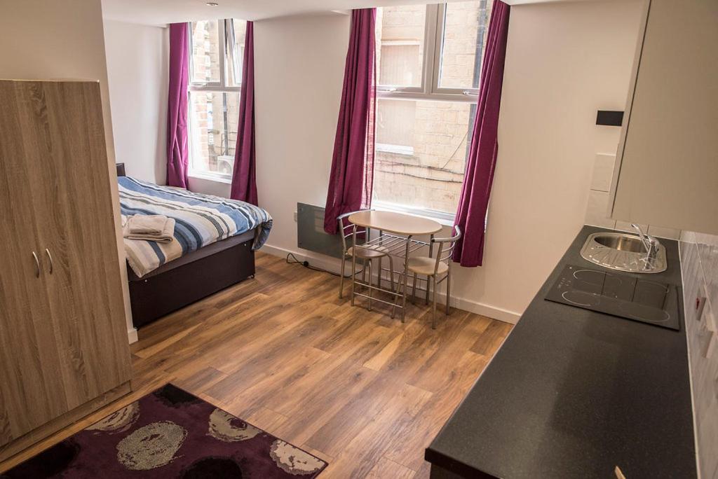 a small room with a bed and a table at Town Centre Apartments in Dewsbury
