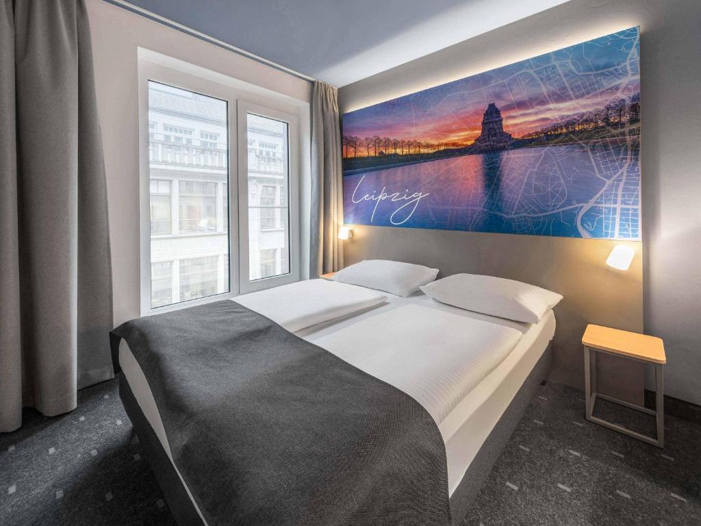 a bedroom with a large bed with a painting on the wall at B&B Hotel Leipzig-City in Leipzig