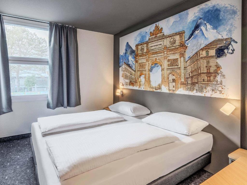 two beds in a room with a painting on the wall at B&B HOTEL München-Schwabing in Munich