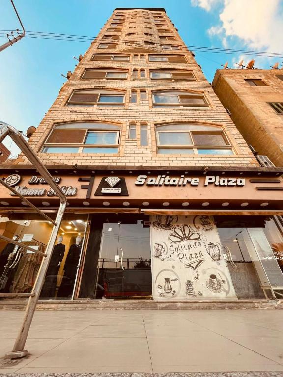 a tall building with a sign in front of it at Solitaire Plaza Hotel-Ismailia سولتير بلازا الاسماعلية in Ismailia