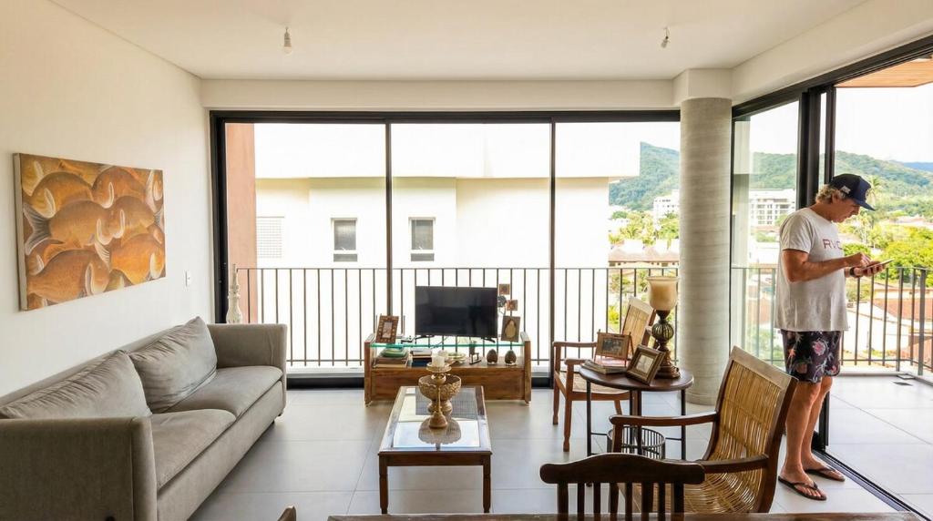 a man standing in a living room looking at his cell phone at Apartamento do Paulão in Ubatuba