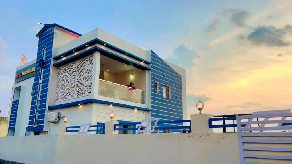a blue and white house with a person sitting on a balcony at Swarnpalace Hotel and Resort in Chaupāran