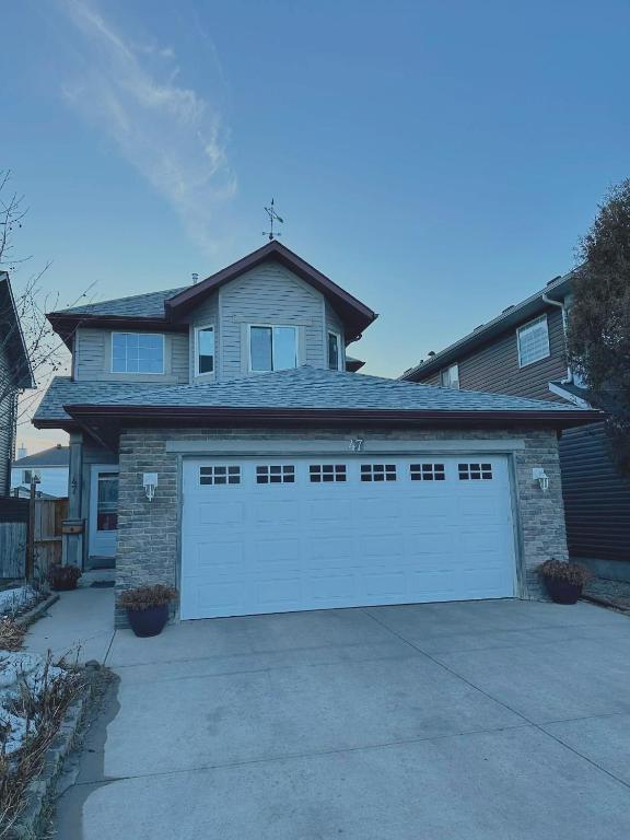 a house with a white garage door in a driveway at Jeli haus in Calgary