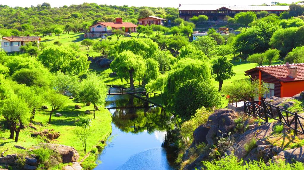 um rio num parque com uma ponte e árvores em Los Ancares Resort em Mina Clavero