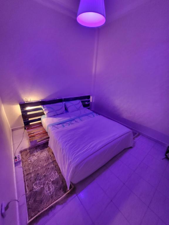 a purple bedroom with a bed with a purple light at your cute house in Salé