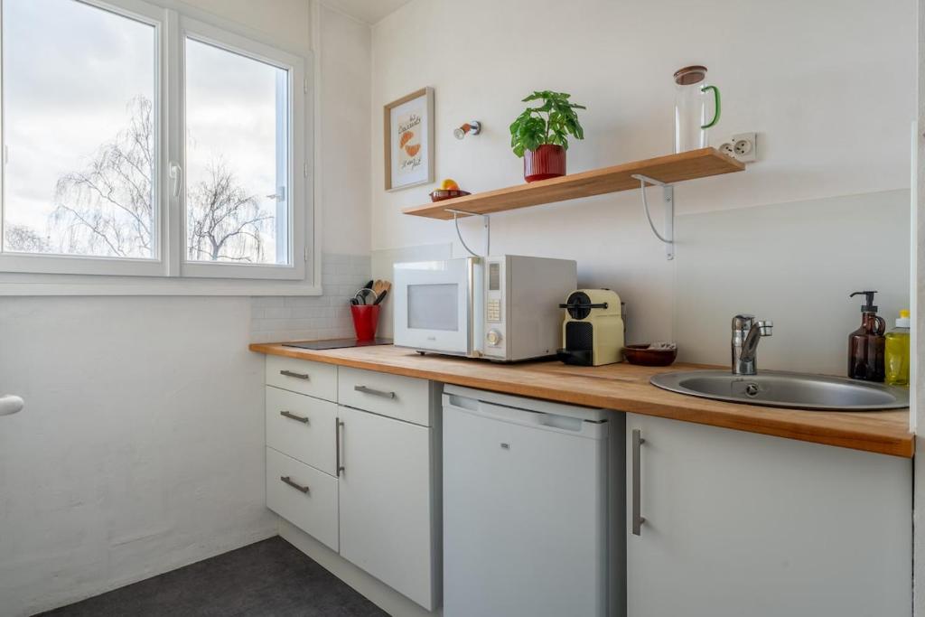 a kitchen with a counter with a microwave and a sink at La Cabane Parking privatif et Balcon in La Riche