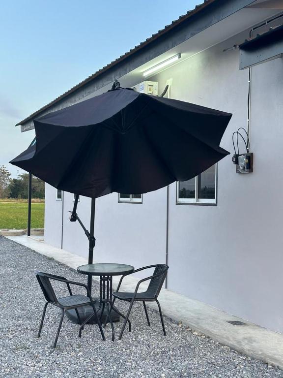 a table and two chairs under an umbrella at Homestay Khan in Arau