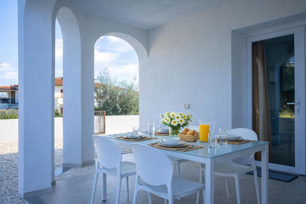 a white dining room with a white table and chairs at Residenza Sa Olia in Budoni