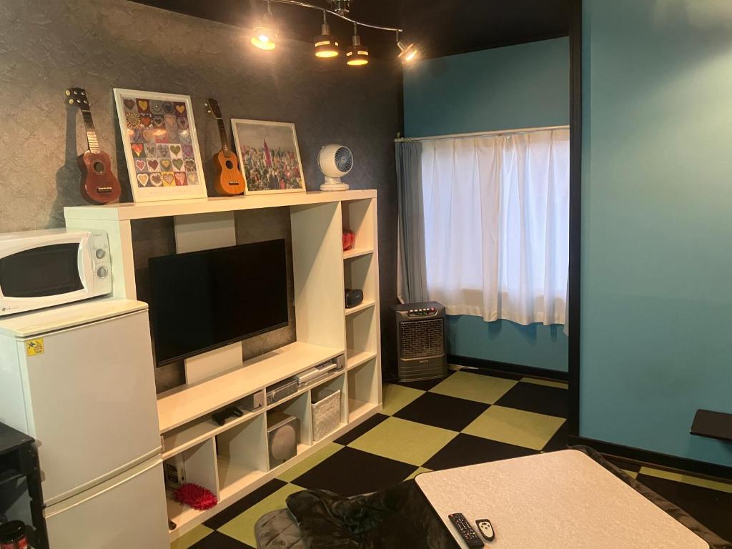a living room with a tv and a white refrigerator at 民泊寿屋Kotobukiya Guesthouse in Muroran