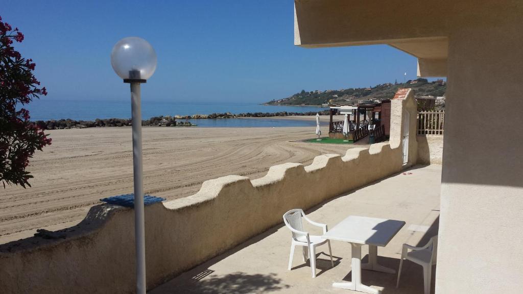 a table and chairs next to a wall next to a beach at Lido Apartments in Sciacca