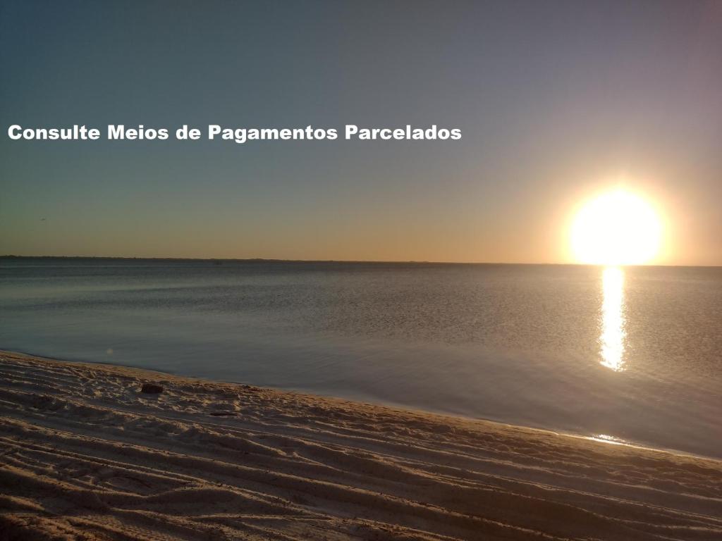 a beach with the sun setting over the water at Vila do Sossego in Cabo Frio