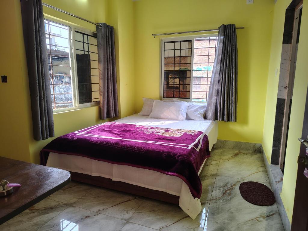 a bed in a room with two windows at Shivmandir Homestay in Siliguri