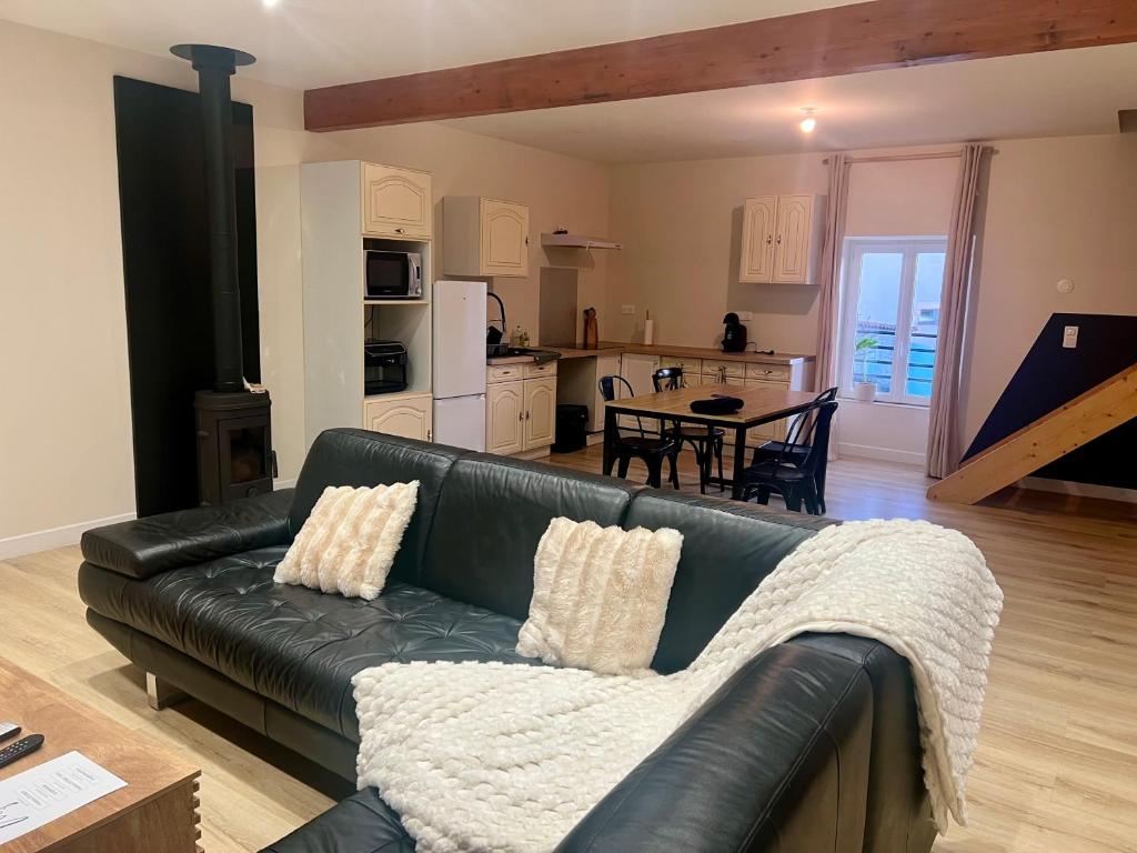 a living room with a black leather couch and a kitchen at Duplex spacieux-2chambres-ideal vehicule electrique in Melle