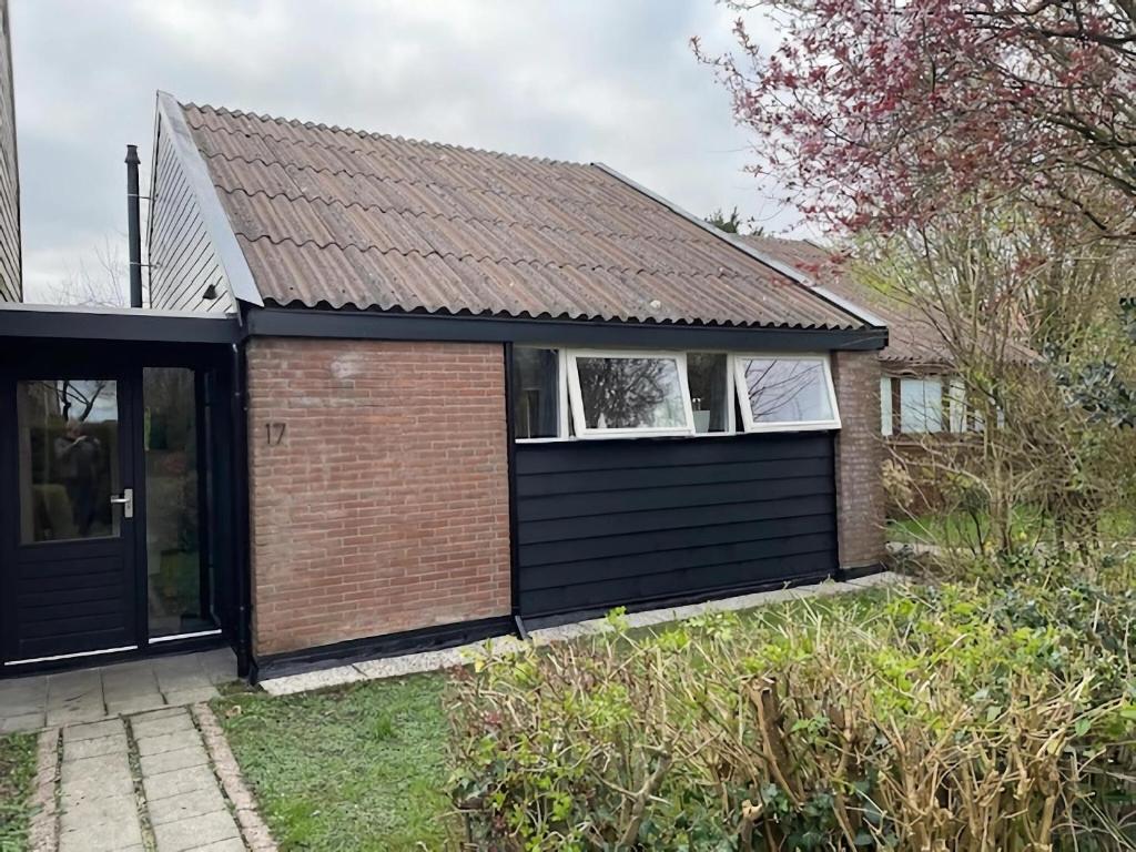 a detached house with a black garage at Holiday Home Warmenhuizen near Dunes in Warmenhuizen
