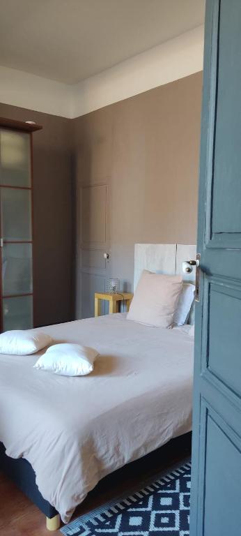 ein Schlafzimmer mit einem Bett mit weißen Laken und Kissen in der Unterkunft Artbnb in Lézat-sur-Lèze