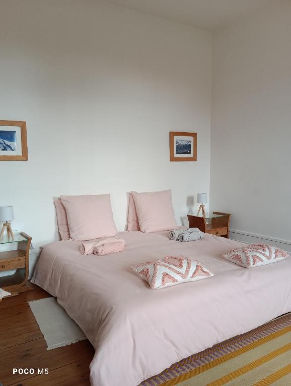 a large white bed with pink pillows on it at Ostal Arriatge in Lézat-sur-Lèze
