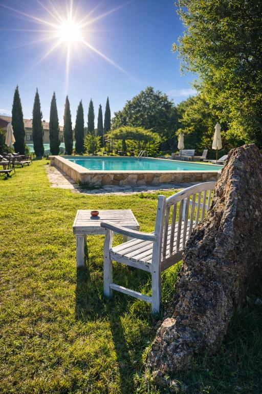 a white bench sitting in the grass near a pool at Il Borgo Del Lupo Relax Family Apartments in Tuscany with Restaurant & Swimming Pool in Sarteano