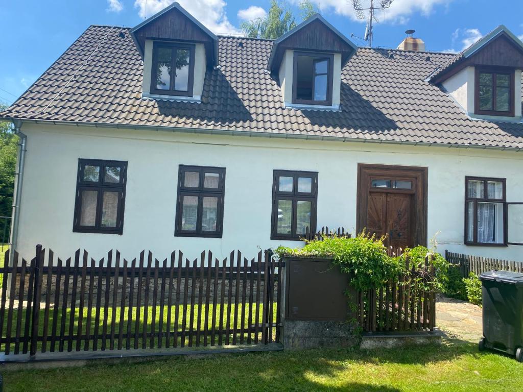 a white house with a black fence at Chalupa Svratouch in Svratouch