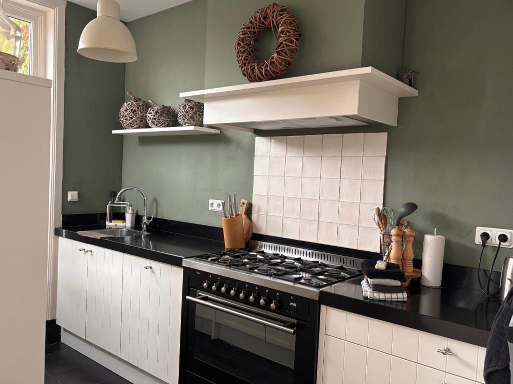 a kitchen with a black stove and white cabinets at Next To Sea in Vlissingen