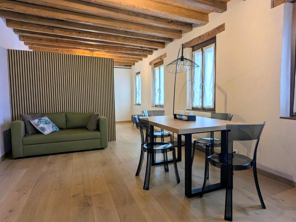 a dining room with a table and chairs and a couch at Locanda alla Nave in Pianzano