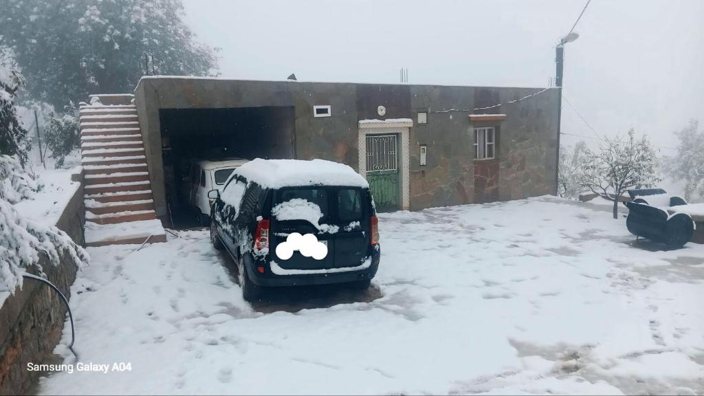 a car covered in snow in front of a house at Tigmi Nlkhir in Aït Irizane