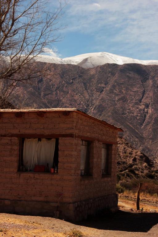 a small brick building with a mountain in the background at Macondo - Casas entre cerros in Tilcara
