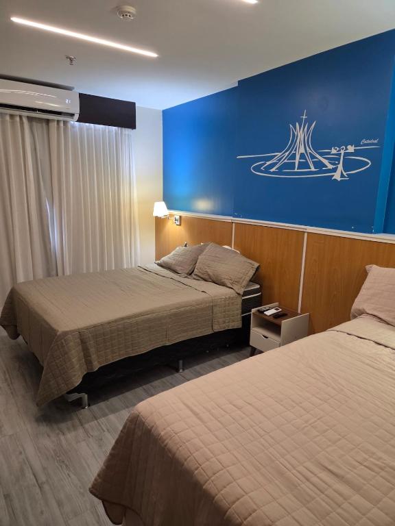 a hotel room with two beds and a blue wall at Flat 811 - Hotel Comfort Taguatinga in Brasília