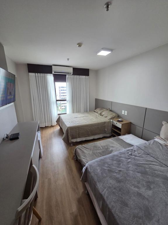 a hotel room with two beds and a desk at Flat 709 - Hotel Comfort Taguatinga in Brasília