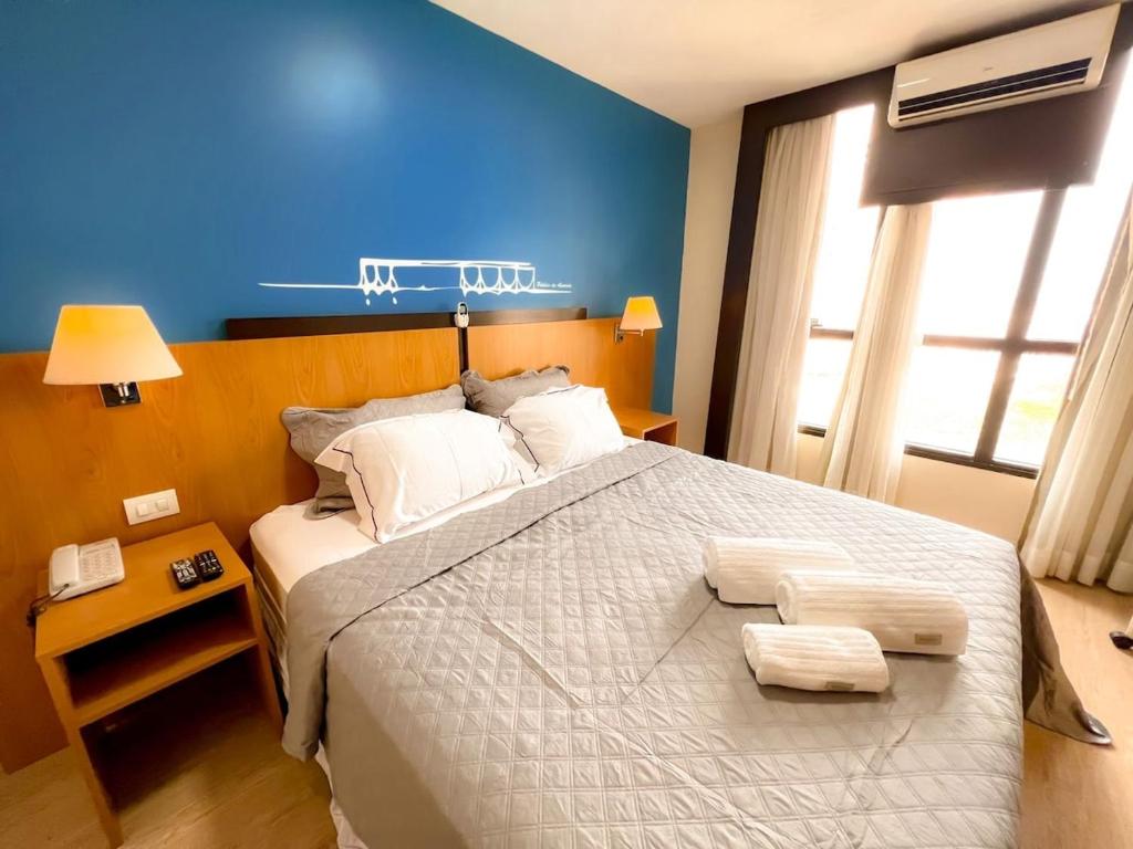 a bedroom with a large bed with a blue wall at Flat 1015 - Hotel Comfort Taguatinga in Brasília