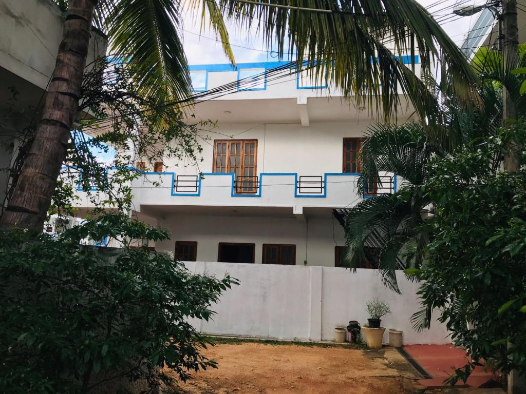 a white house with a blue balcony on it at Blue Deer Villa in Trincomalee
