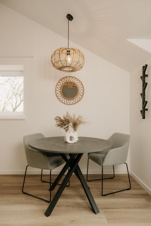 a dining room table with chairs and a light fixture at De Vlaeke in Kerkwerve