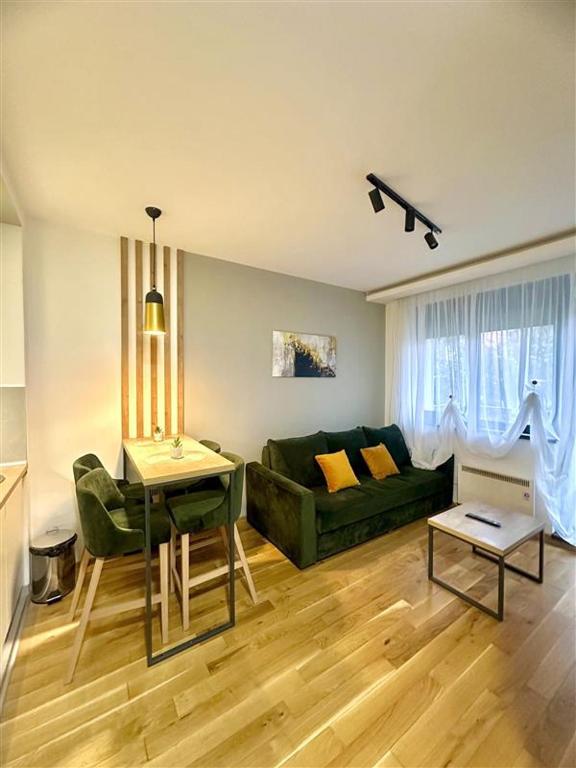 a living room with a green couch and a table at Emerald Mamba - Titova Vila in Zlatibor