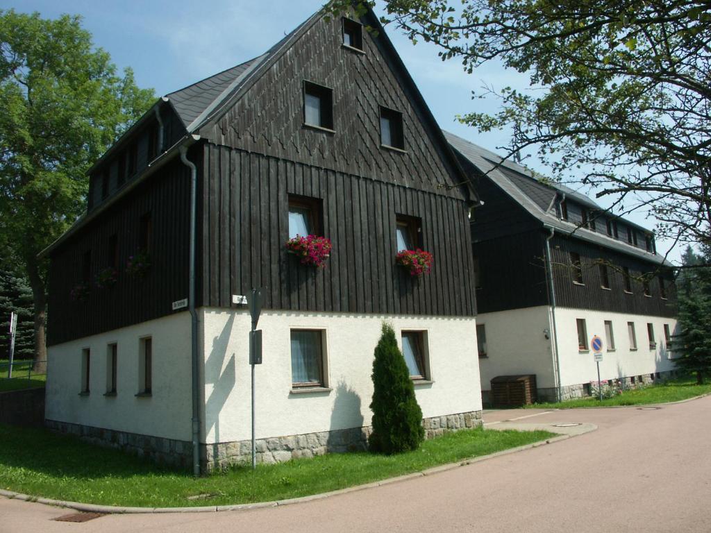 ein schwarzweißes Gebäude mit Blumen in den Fenstern in der Unterkunft Apartments Ski Sonne Rehe in Rehefeld-Zaunhaus