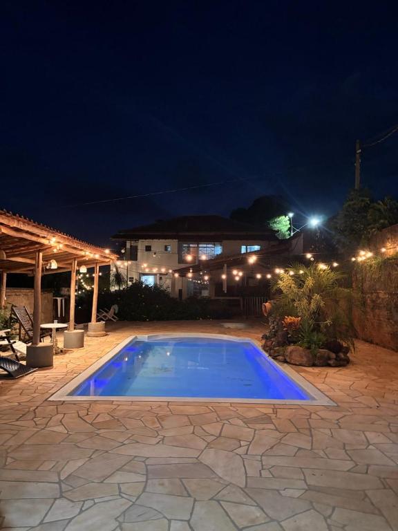 a large blue swimming pool in a yard at night at Pousada DrChico in Poço Fundo