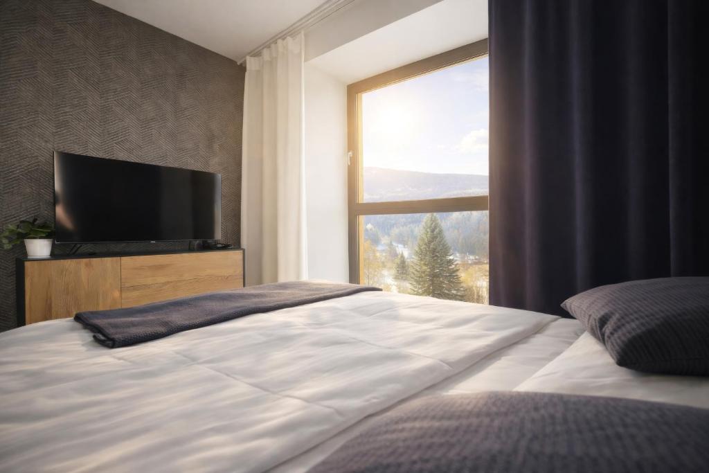 a bedroom with a large bed with a large window at Javorná - Aura a Nord in Čachrov
