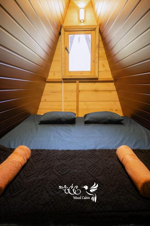 a bedroom in a tiny house with a window at Kedella wood cabin in Nuwara Eliya