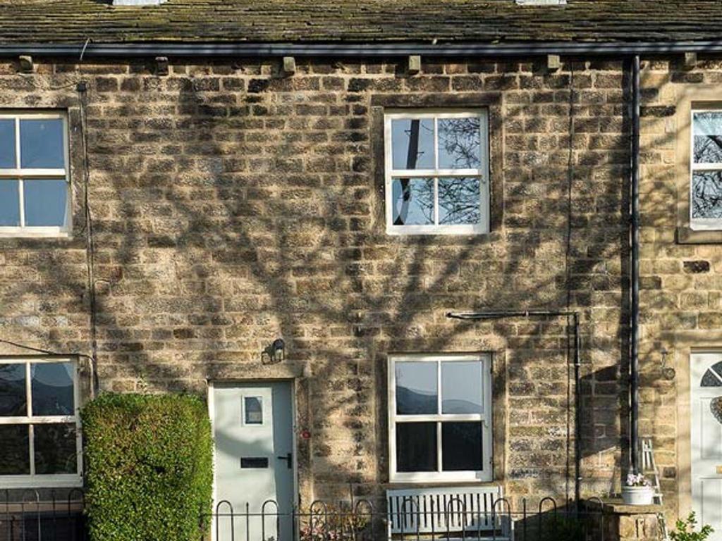 a brick building with a white door and windows at Beacon Cottage in Ilkley
