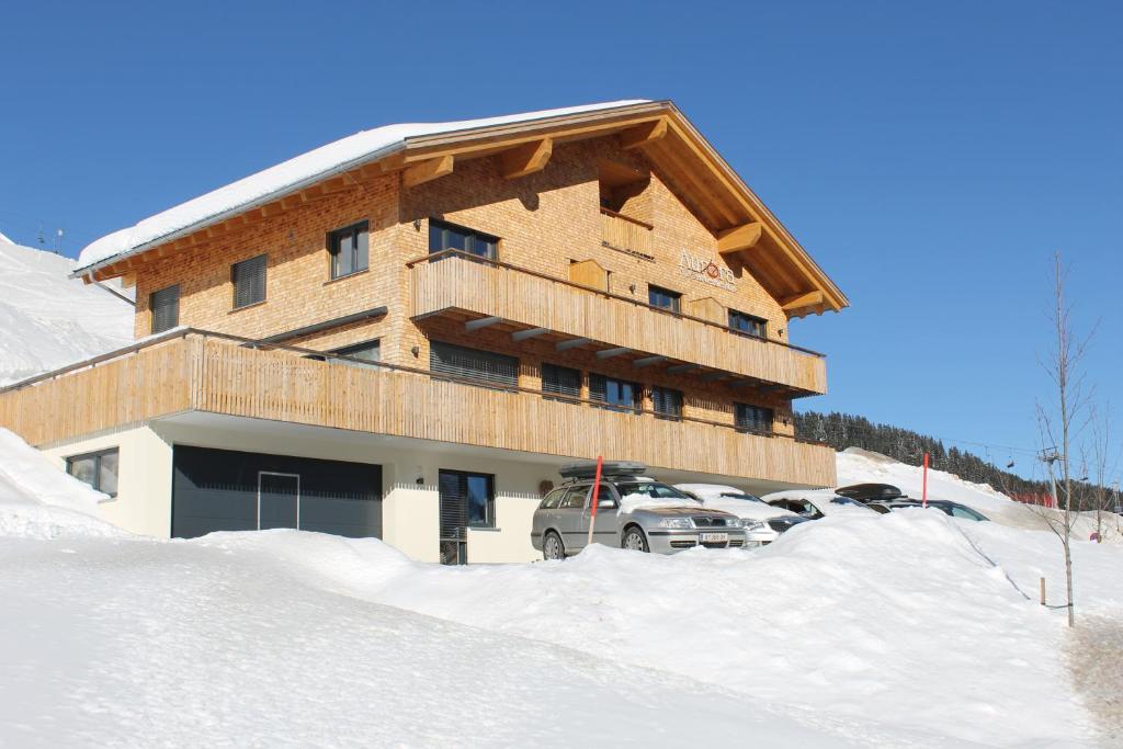 a large building with cars parked in the snow at Appartements Aurora in Damuls