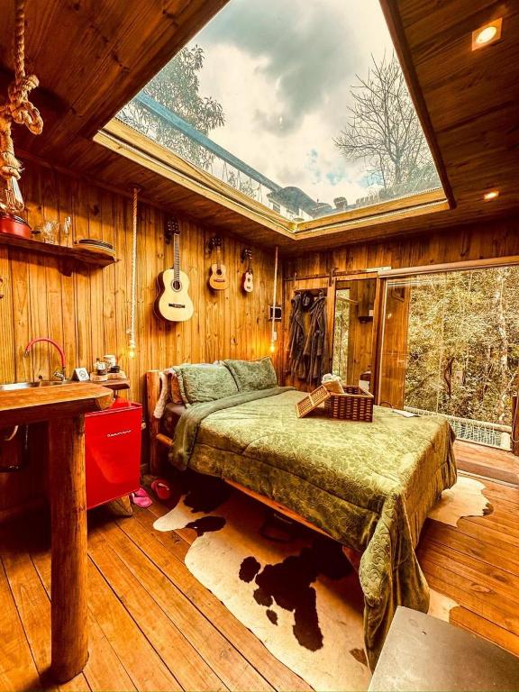 a bedroom with a bed with a large window at Cabana da Árvore e Cabana Retrô - ForestPlace in Monte Verde
