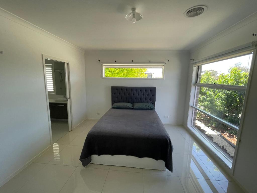 a bedroom with a bed and two windows at Master's bedroom in Mount Duneed in Mount Duneed