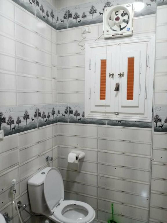 a white bathroom with a toilet and a cabinet at راس البر المستشارين in ‘Izbat ash Sharāyid