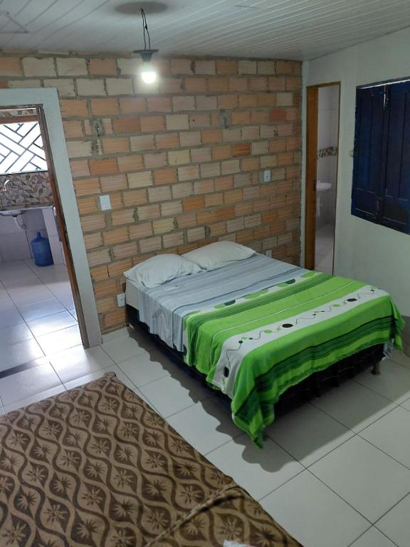 a bed in a room with a brick wall at SUÍTE Botos De Alter in Alter do Chao