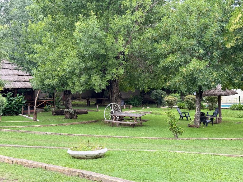 a park with a picnic table and benches and trees at Cabañas La Cautiva in Tanti