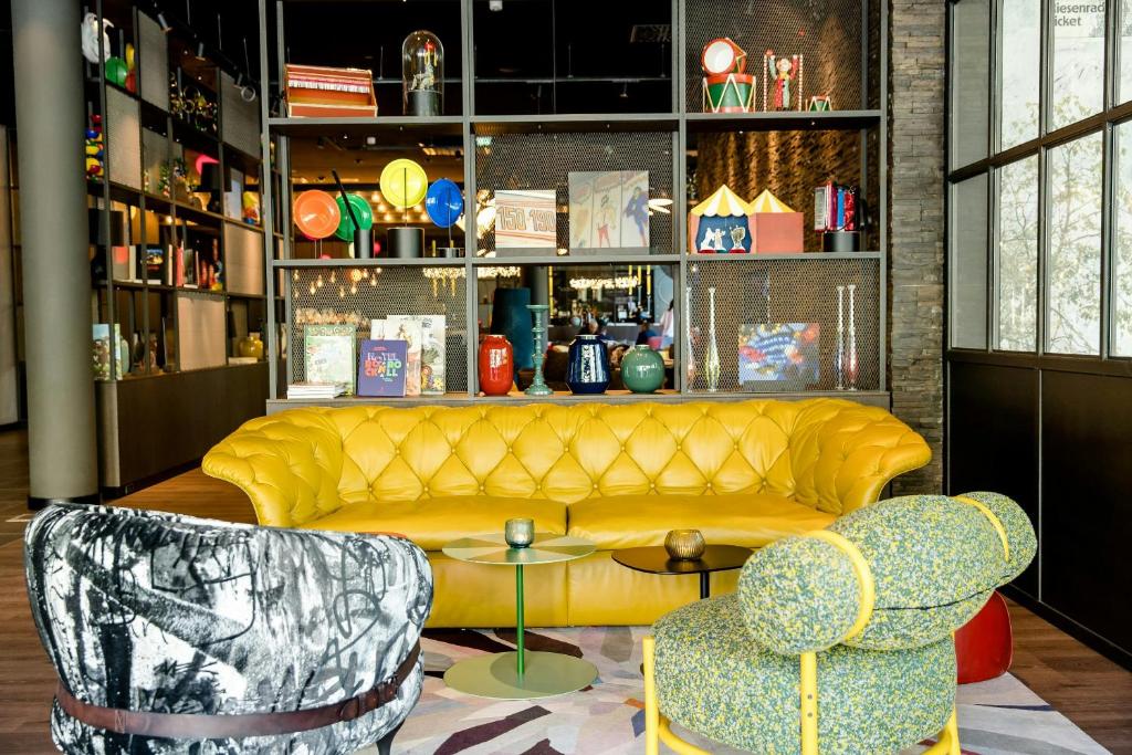 a living room with a yellow couch and two chairs at Motel One Wien-Prater in Vienna