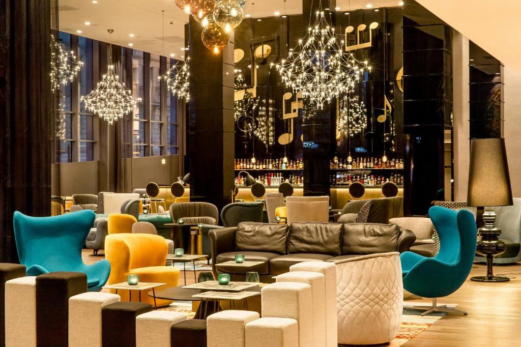 a lobby with couches and tables and chandeliers at Motel One Warsaw-Chopin in Warsaw